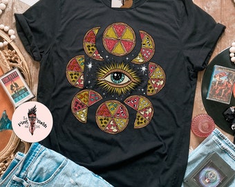 May include: Black t-shirt with a graphic of a large eye surrounded by pizza slices. The pizza slices are arranged in a circle around the eye, and each slice has a different topping. The background is a dark blue with stars.