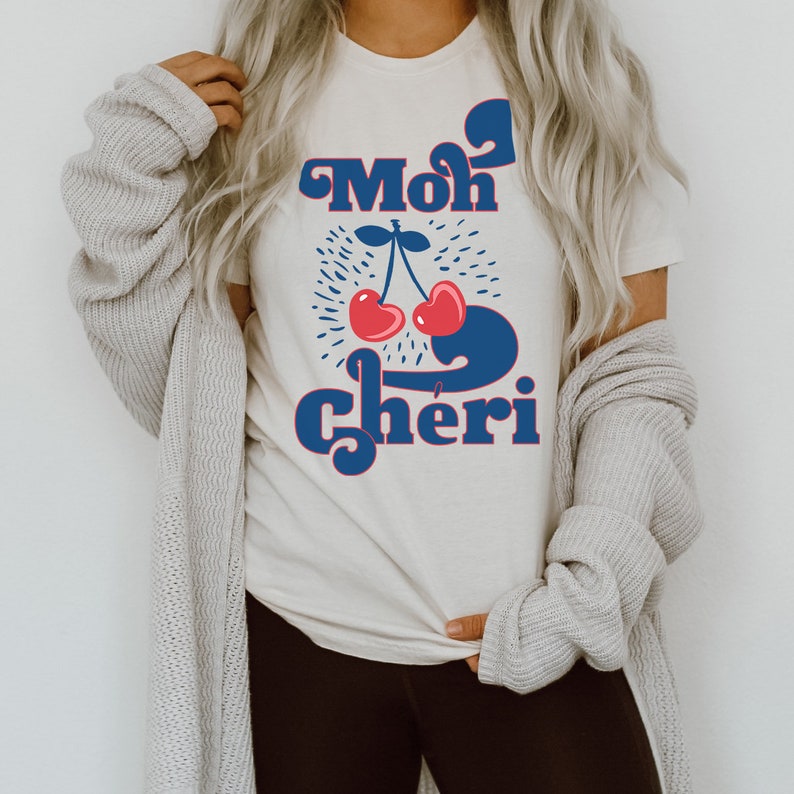 May include: A white t-shirt with a blue and red graphic design that says "Mon Cheri" with a cherry illustration.