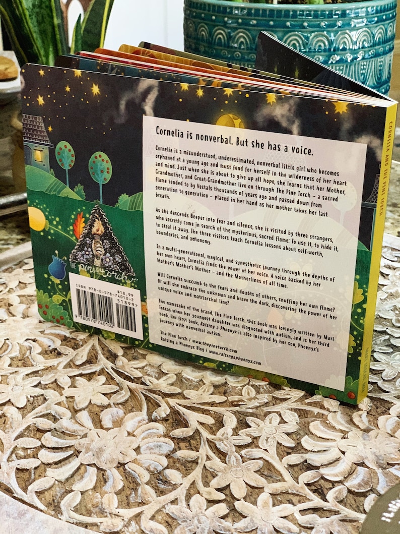 May include: The back cover of a children's book titled "Cornelia and the Fine Torch." The book features a colorful illustration of a girl holding a torch. The text describes the story of a nonverbal girl who finds her voice.