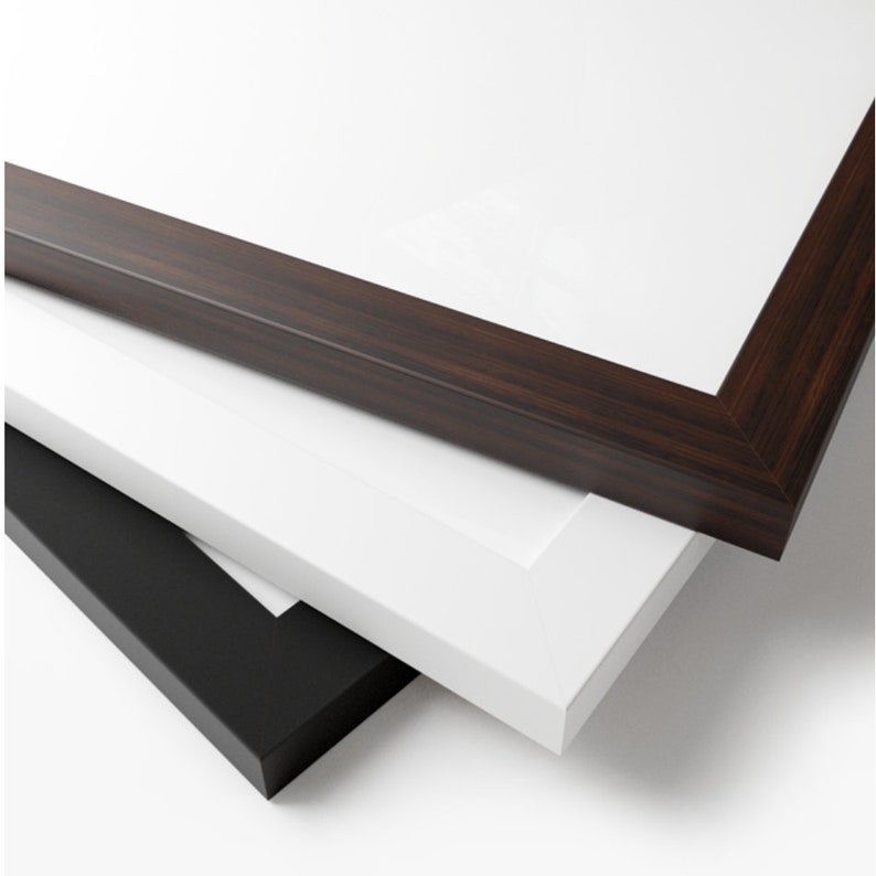 May include: Three picture frames stacked on top of each other. The top frame is dark brown wood, the middle frame is white, and the bottom frame is black.