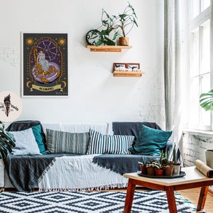 May include: A framed illustration of the zodiac sign Scorpio. The illustration features a woman sitting on a scorpion with a starry background. The text "Scorpio" is written in a banner below the image.