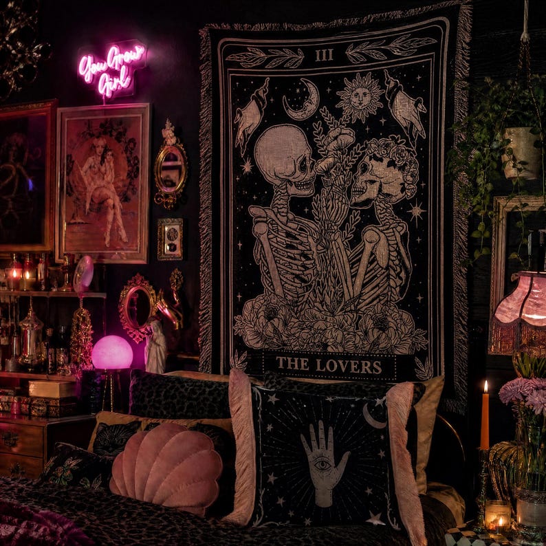 May include: A dark room with a black and white tapestry featuring skeletons and the text "THE LOVERS." The room includes a bed with decorative pillows, a neon sign that says "You Grow Girl," and various framed artworks and mirrors.