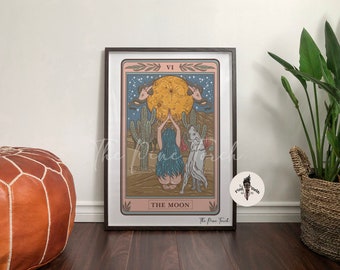 May include: A tarot card illustration of The Moon card. The card features a woman with long blue hair standing with her arms raised, a white wolf standing beside her, and a large yellow moon in the background. The card is framed in a black frame and has the text "VI THE MOON" at the bottom.