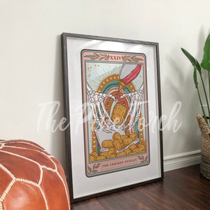 May include: A tarot card illustration with a skeleton holding a box of chicken nuggets. The card is titled "The Chicken Nugget" and is framed in a black frame.