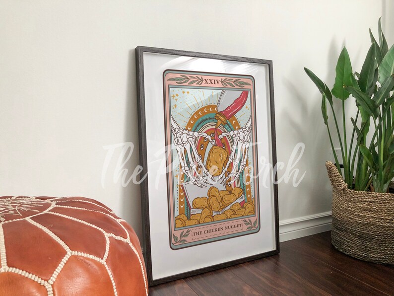 May include: A tarot card illustration with a skeleton holding a box of chicken nuggets. The card is titled "The Chicken Nugget" and is framed in a black frame.