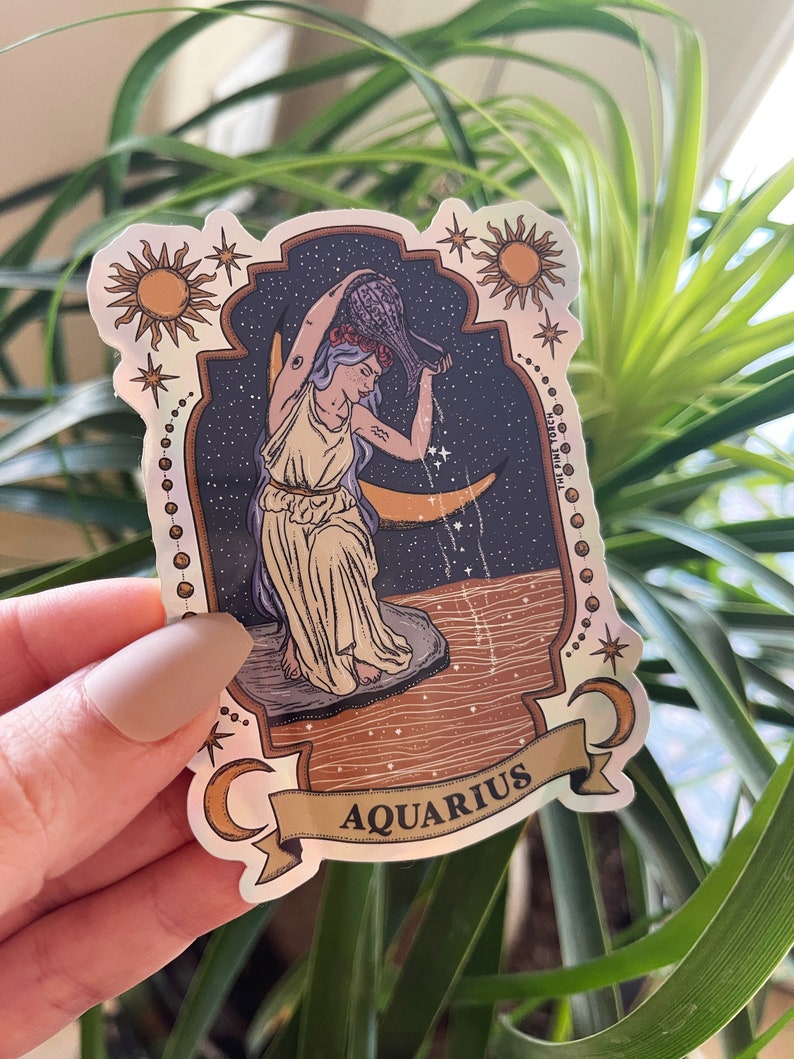 以下が含まれることがあります： ホログラフィックステッカー。水瓶座の星座のイラストが特徴です。デザインには、星空と三日月を背景に、水瓶から水を注ぐ女性が描かれています。「AQUARIUS」の文字がバナーに表示されています。