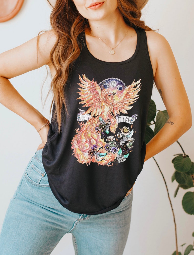 May include: Black tank top with a graphic print of a phoenix with flames and flowers. The text "Light my fire" is printed on the graphic.
