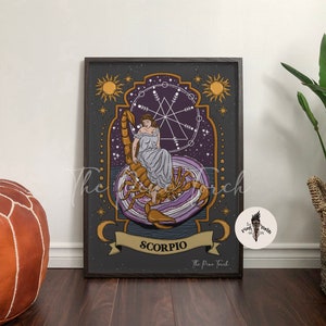 May include: A dark gray and purple illustrated print of the zodiac sign Scorpio. The image features a woman sitting on a scorpion with a starry background and a geometric design. The text "Scorpio" is written in gold lettering at the bottom of the print.