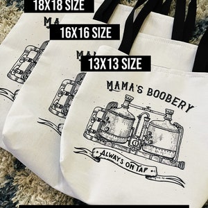 May include: Three white canvas tote bags with black handles and black text. The bags are stacked on top of each other, with the largest bag on the bottom. The bags are labeled with the sizes 18x18, 16x16, and 13x13. The smallest bag has a black and white illustration of a brewery with the text "Mama's Boobery" and "Always on Tap".