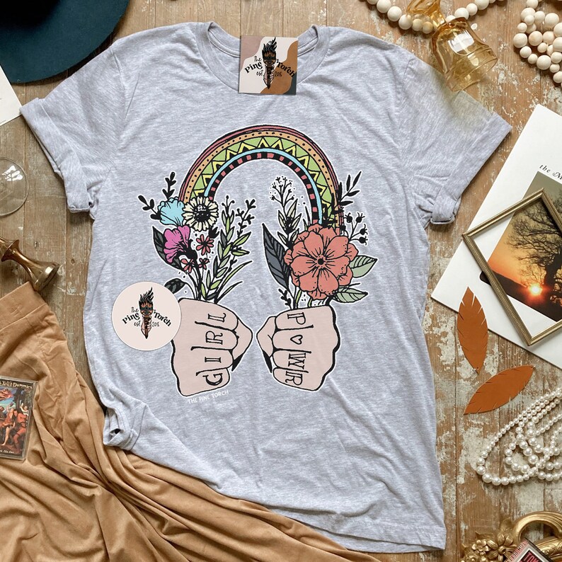 May include: Gray t-shirt with a rainbow and flowers graphic. The graphic features two fists with the words "Girl" and "Power" written on them.