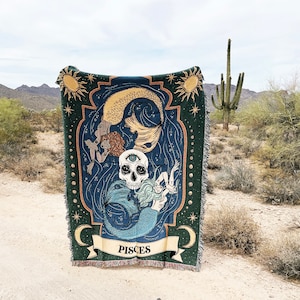 Op de afbeelding: Een groene wandkleed met een blauw en gouden ontwerp met een zeemeermin met een schedelkop en de tekst "Pisces".