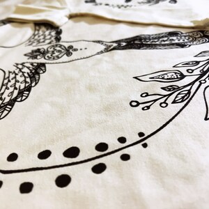 May include: A white fabric tote bag with a black and white illustration of a bird and floral design.