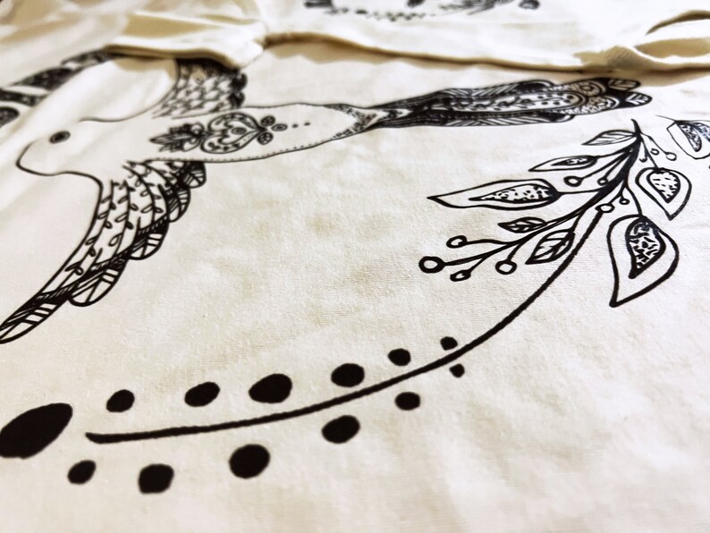 May include: A white fabric tote bag with a black and white illustration of a bird and floral design.