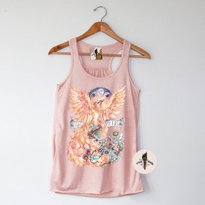 May include: A pink tank top with a graphic of a phoenix with the text "Light My Fire" printed on it. The phoenix is surrounded by flowers and fire.