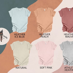 May include: Six different colored t-shirts with ruffled edges. The colors are heather ice blue, heather peach, heather mauve, natural, soft pink, and athletic heather.