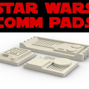 Puede incluir: Tres placas de comunicación de Star Wars de plástico beige. Las placas son rectangulares y tienen varios botones y perillas.
