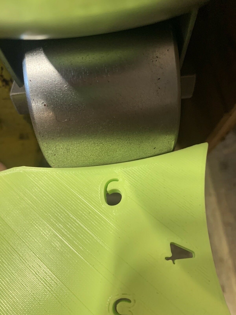 May include: A lime green plastic part with a number "6" and a small arrow symbol. The part is attached to a metal wheel.