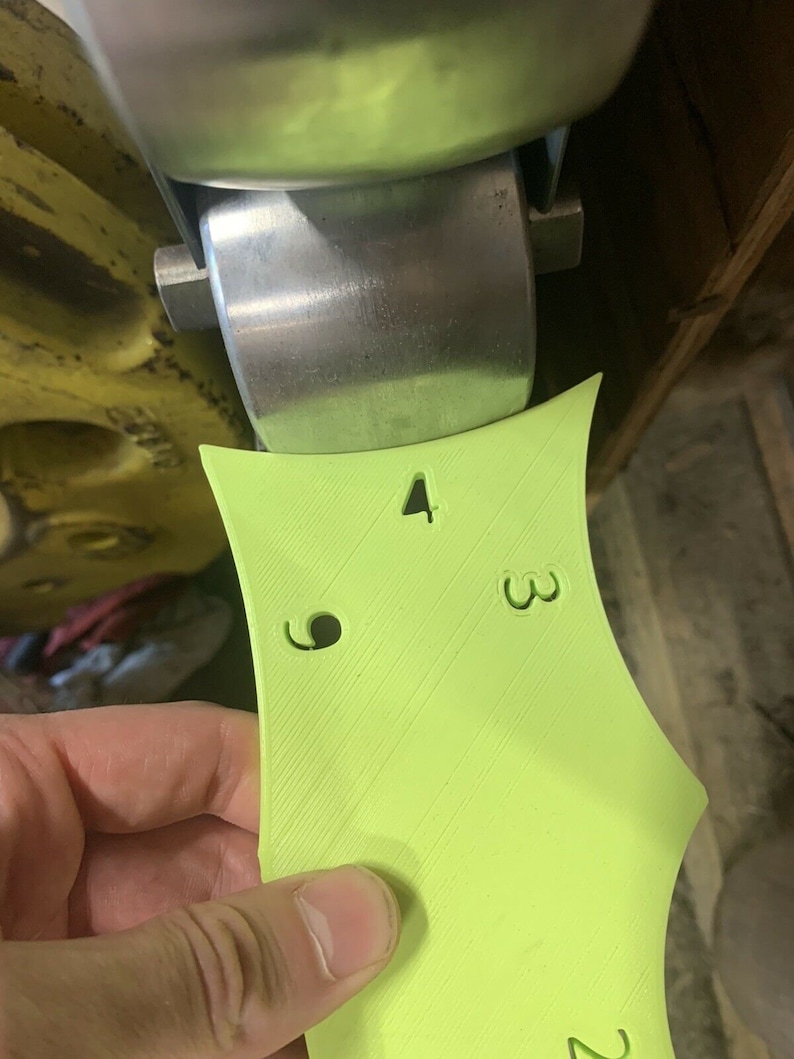 May include: A lime green plastic template with numbers 2, 3, and 4 printed on it. There are two holes in the template.
