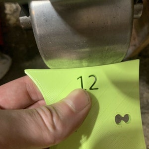 May include: A lime green plastic sign with the number "12" printed on it. The sign has a small hole in the shape of an infinity symbol.