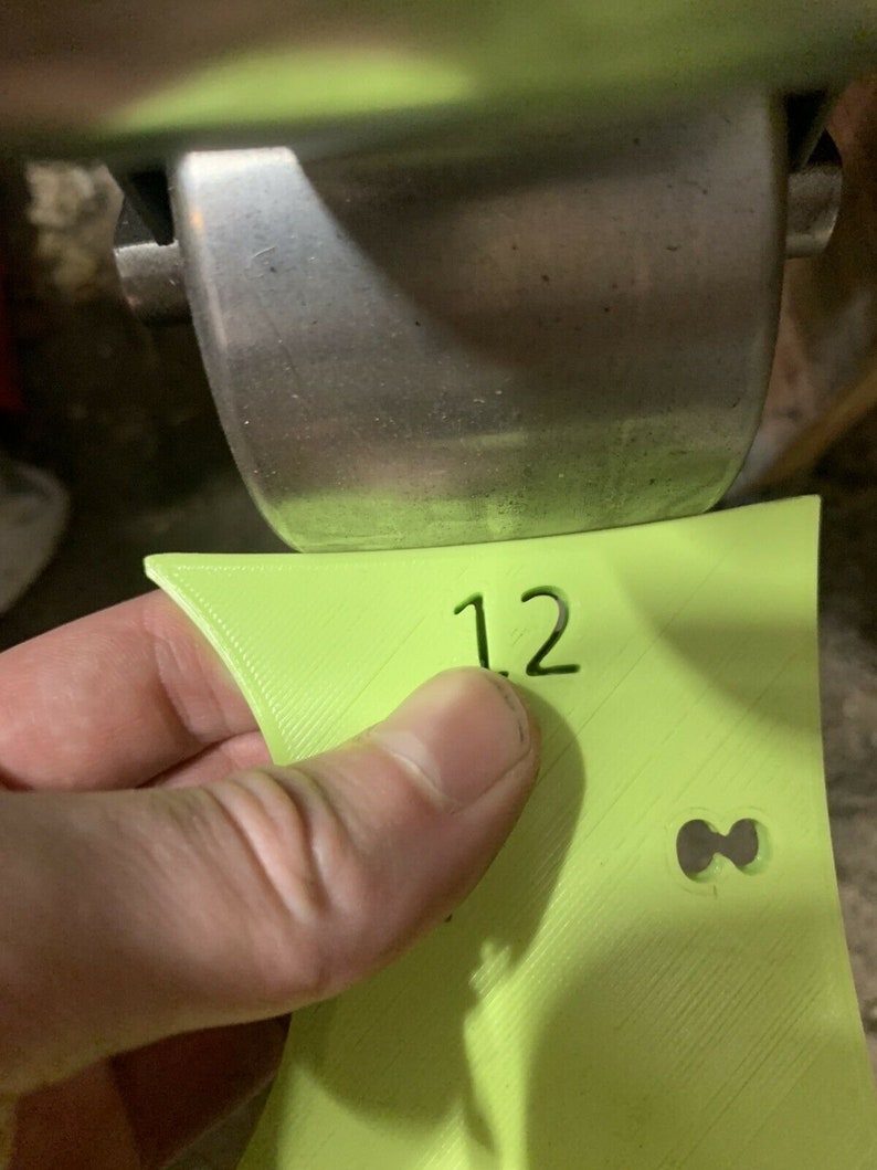 May include: A lime green plastic sign with the number "12" printed on it. The sign has a small hole in the shape of an infinity symbol.