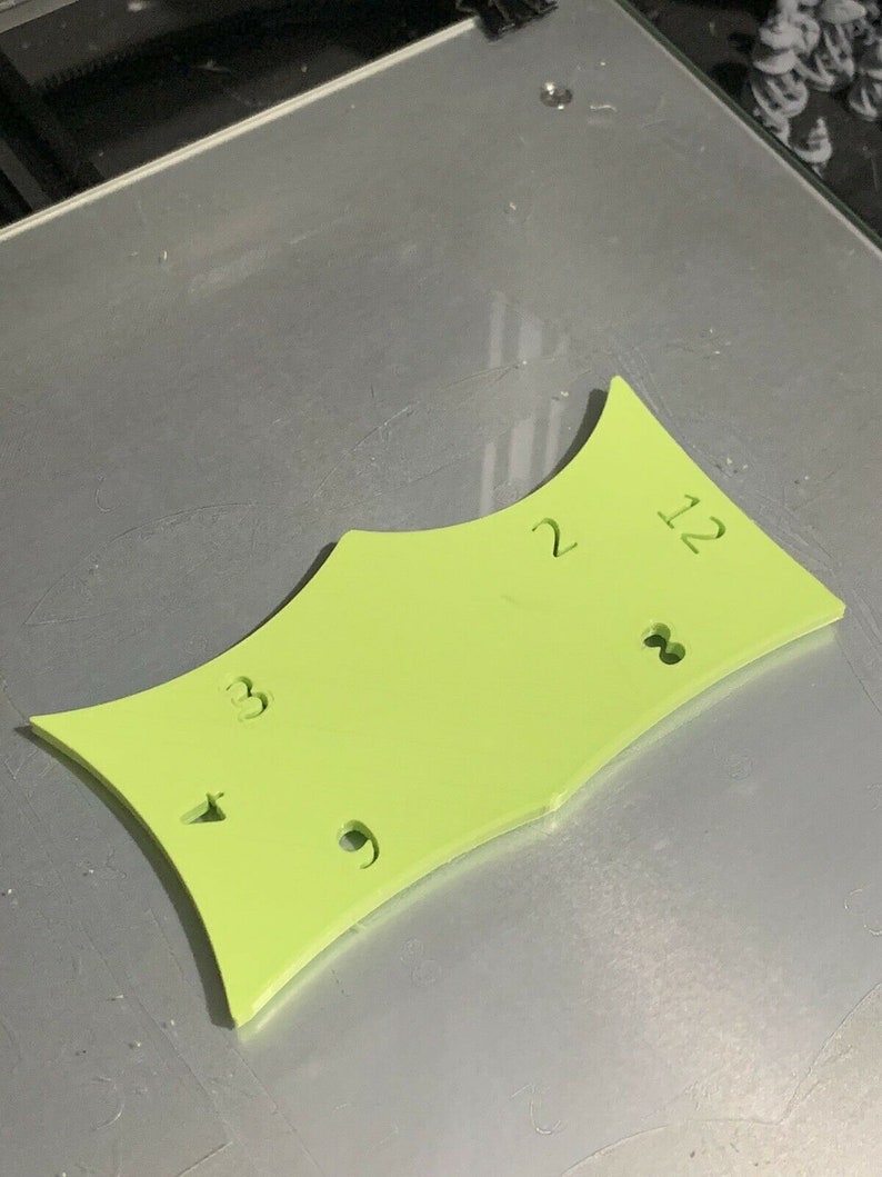 May include: A lime green plastic template with the numbers 2, 12, 3, and 9 printed on it.