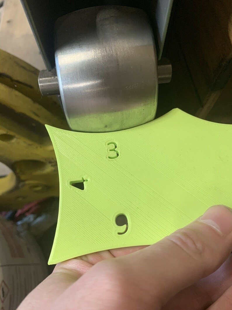 May include: A green plastic measuring tool with the numbers 3, 4, and 9 printed on it. The tool is being used to measure a metal wheel.