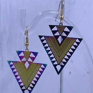 May include: A pair of iridescent gold and black triangle earrings with geometric designs. The earrings have a gold hook closure.
