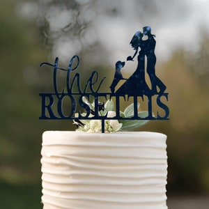 May include: A white wedding cake with a black silhouette cake topper featuring a couple kissing and a dog. The topper says "The Rosettis".