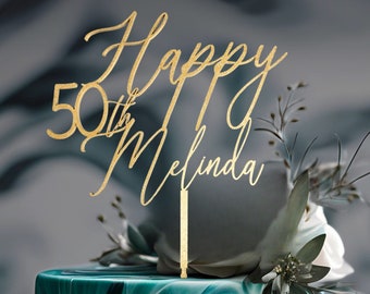 May include: Gold glitter cake topper with the text "Happy 50th Melinda" on a green and white marbled cake.