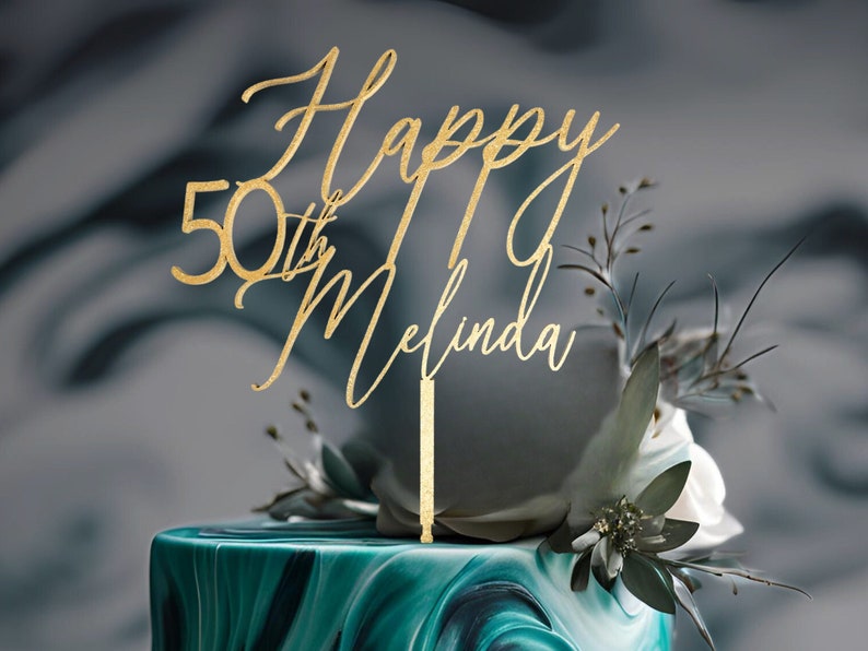 May include: Gold glitter cake topper with the text "Happy 50th Melinda" on a green and white marbled cake.