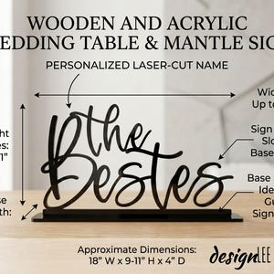 May include: Black wooden and acrylic wedding table sign with the text "The Bestes" in a cursive font. The sign is laser-cut and sits in a base stand. Approximate dimensions are 18" W x 9-11" H x 4" D.