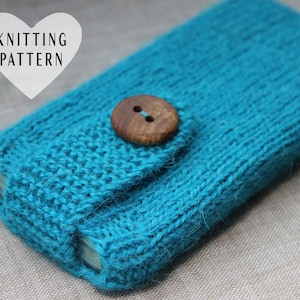 May include: A knitted teal phone case with a wooden button closure. The case is made of a textured yarn and features a flap that secures with a round, two-hole button. The words "KNITTING PATTERN" are in a white heart-shaped graphic.
