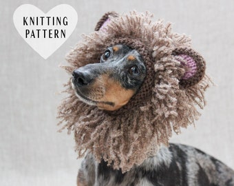 May include: A dachshund dog wearing a brown and pink knitted lion costume. The costume has a fluffy mane and ears. The dog is looking up and to the right. The text "Knitting Pattern" is in a white heart shape in the upper left corner of the image.