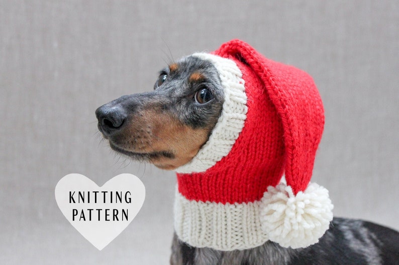 May include: A dachshund wearing a red and white knitted Santa hat with a white pom-pom. The hat has a long, pointed tip. The dog is looking to the left. The text "KNITTING PATTERN" is in a white heart shape.