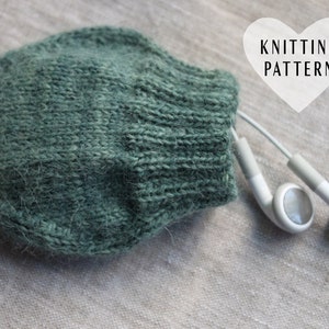 May include: A green knitted earbud holder with white earbuds. The holder is made with a soft, fuzzy yarn. The image includes the text "Knitting Pattern".