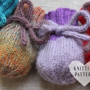 May include: Four knitted drawstring bags in different colors: teal, orange, purple, and red. The bags are tied with brown yarn and have a "Knitting Pattern" label.