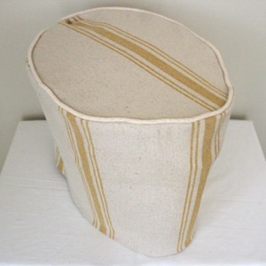 May include: A white and yellow striped fabric cover for a kitchen appliance. The cover has a rounded top and a straight bottom.