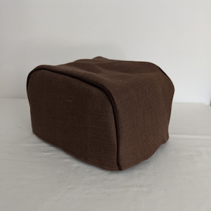 Könnte beinhalten: Ein brauner Toasterbezug aus Leinen mit dunkelbraunem Besatz.