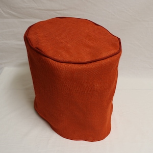 May include: Orange burlap fabric storage ottoman with a red trim around the top.