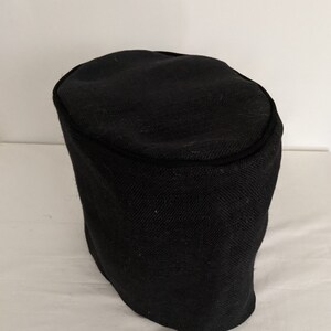 May include: Black fabric cover for a kitchen appliance. The cover is made of a textured material and has a black trim around the top edge.