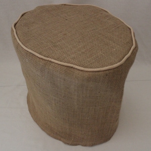 Może przedstawiać: Brązowy otoman z tkaniny jutowej z białą lamówką wokół górnej krawędzi.