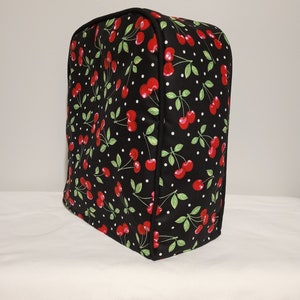 Könnte beinhalten: Schwarze Küchen-Geräteabdeckung mit einem Kirsch- und weißen Tupfenmuster.