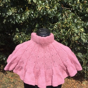 Op de afbeelding: Een roze gebreide cowl met een gerimpelde rand. De cowl is gemaakt van een zacht, lichtgewicht garen en heeft een delicaat opengewerkt patroon.