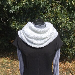 May include: White knitted cowl neck scarf. The scarf is thick and warm, perfect for cold weather.