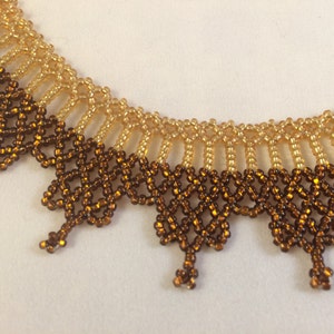 May include: A beaded necklace with a brown and gold color gradient. The necklace is made of small, round beads that are woven together in a delicate pattern.
