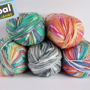 Könnte beinhalten: Fünf Knäuel buntes Garn in Pyramidenform. Das Garn ist mehrfarbig mit Streifen in Weiß, Rosa, Orange, Gelb, Grün, Blau und Grau. Das Garn ist mit "Opal 25 Jahre" gekennzeichnet.