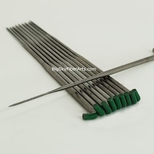 May include: A set of 10 green-tipped, stainless steel needles for felting. The needles are arranged in a stack with one needle laying across the top. The needles are used for needle felting, a craft that uses needles to create three-dimensional sculptures from wool fibers.