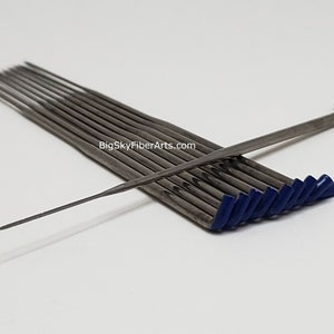 May include: A set of 12 blue-tipped, stainless steel felting needles. The needles are arranged in a fan shape with one needle laying across the top. The needles are used for felting wool and other fibers.