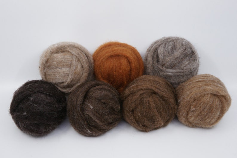 May include: A collection of eight balls of natural-colored wool yarn. The colors range from dark brown to light beige, with a vibrant orange ball in the center. The yarn appears soft and fluffy, ideal for knitting or other fiber crafts.