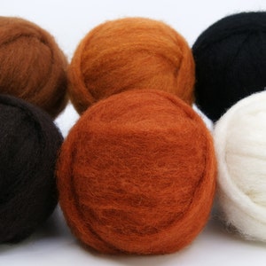 May include: A collection of six wool roving balls in various colors. The colors include shades of brown, orange, black, and white. The balls are round and fluffy, ideal for fiber art projects like needle felting or spinning.